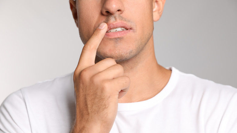 man touching lip with index finger