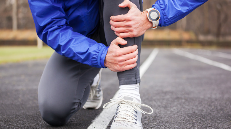 Cropped shot of a runner holding his leg in pain