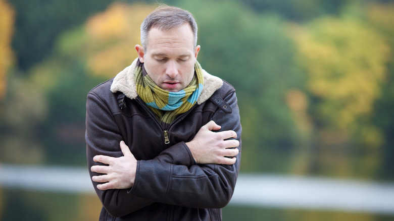 Man in winter clothes hugging himself