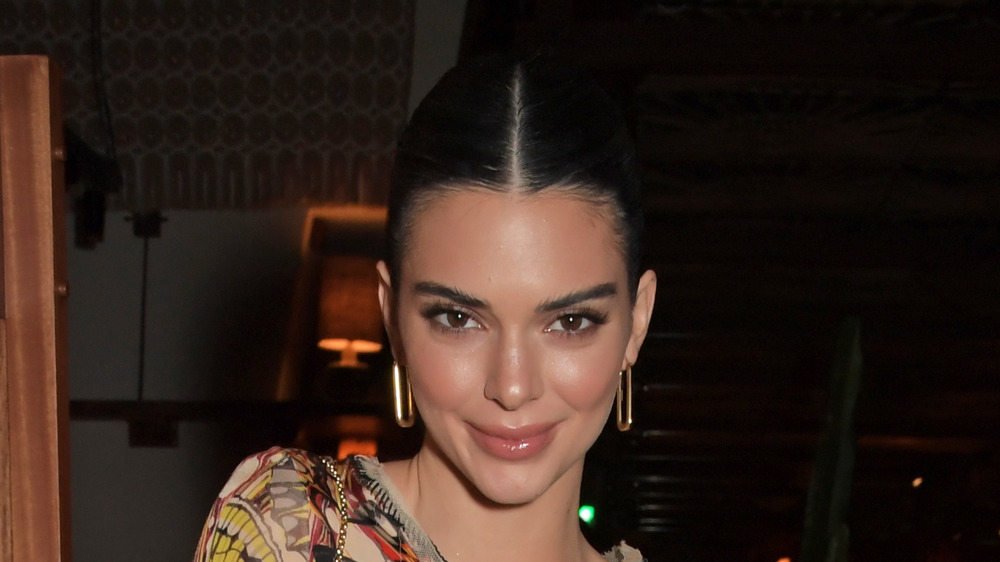 Kendall Jenner with sleeked back hair smiling at camera 