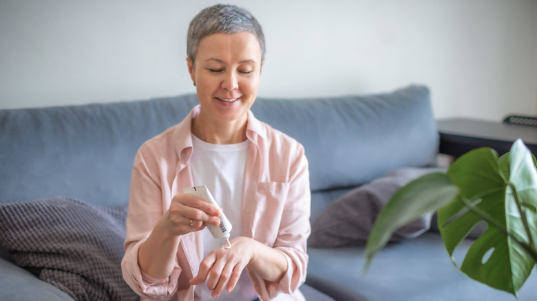 Smiling woman applying hand cream