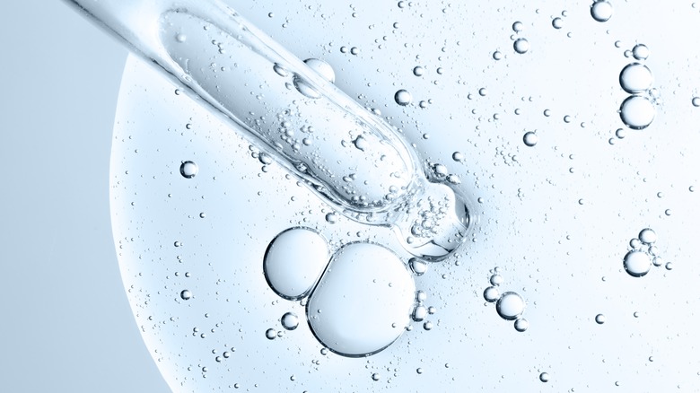 Closeup of dropper with facial serum and bubbles