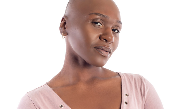 bald woman wearing pink bloiuse