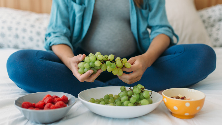 pregnant woman on bed eating healthy snacks