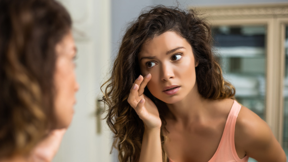 woman looking in mirror at eye