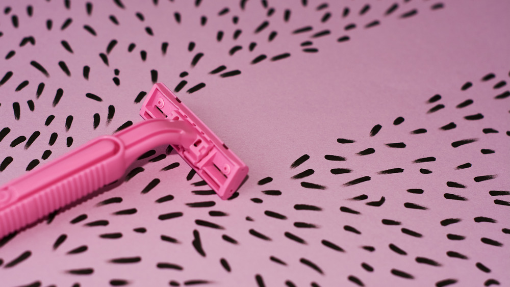 pink razor and hair on pink background
