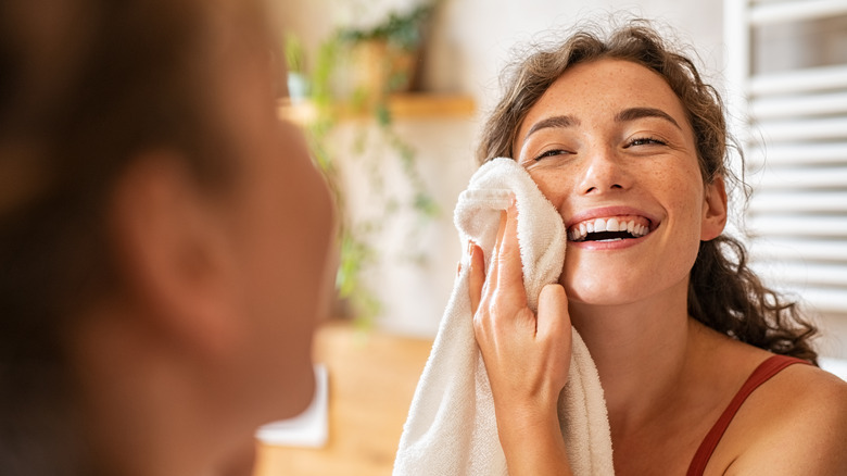 A woman wipes her face with a towel