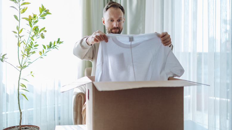 man unpacking box of new clothes