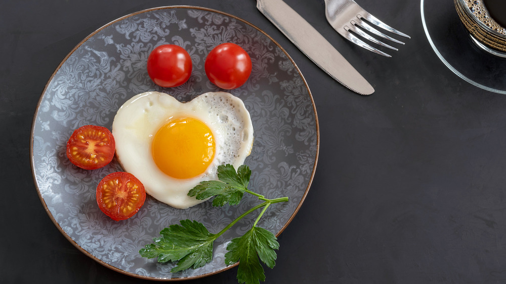 woman making a heart symbol with her hands and an egg