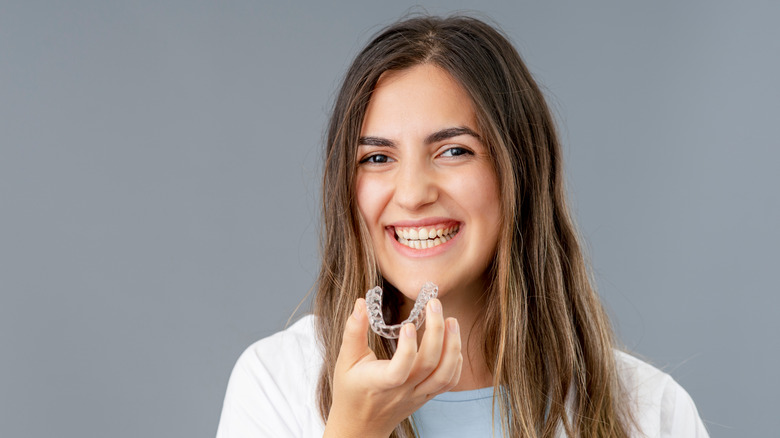 A woman smiles with an Invisalign tray