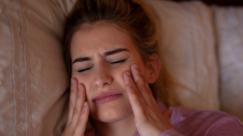 Woman clenching her jaw in bed