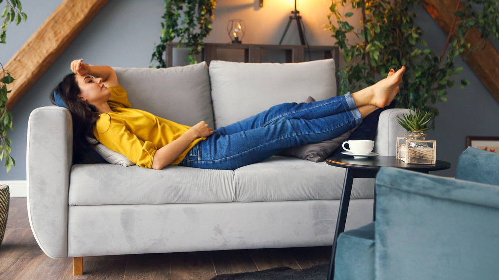 woman napping on the couch with a cup of coffee on the table 