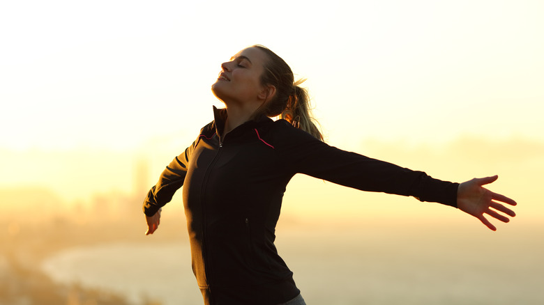 Woman taking a deep breath with outstretched arms