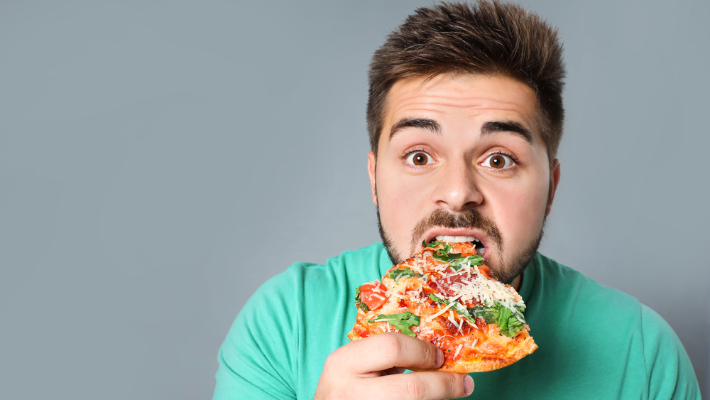 Man biting into a piece of pizza
