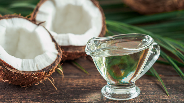 Liquid MCT oil and halved coconut on wooden table