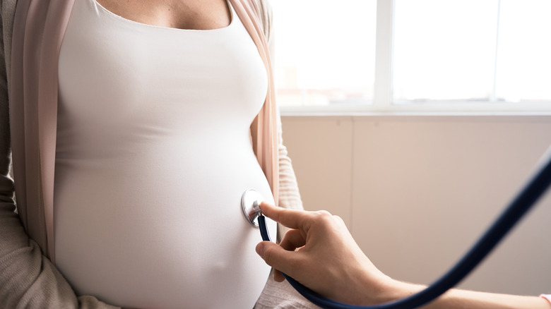 Doctor examines pregnant belly for baby and mother healthcare check up