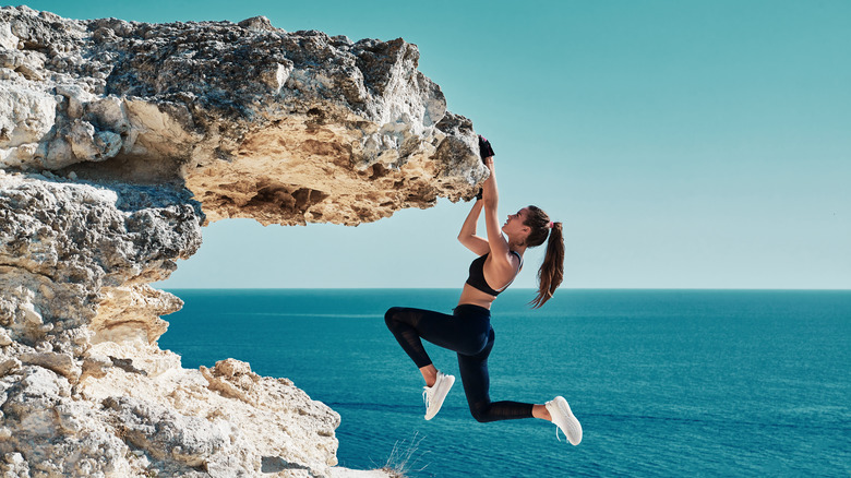 fit woman hanging off the edge of a cliff 