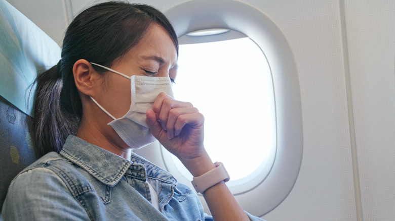 Woman coughing wearing mask on a plane