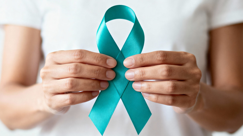 woman's hands holding teal ribbon for cervical cancer awareness