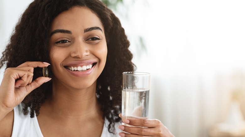 woman shaking vitamins into hand