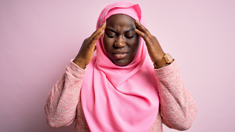 woman holding head in pain
