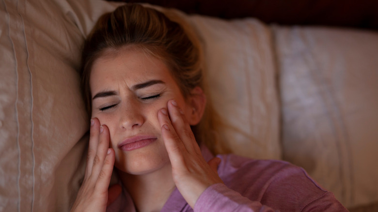 woman touching jaw in pain
