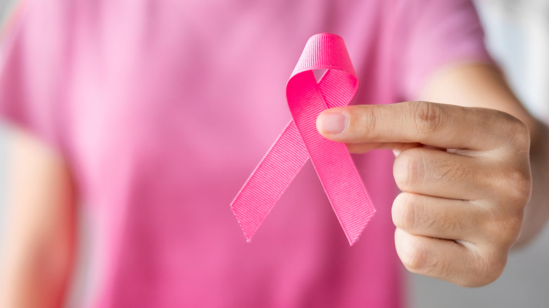 woman holding pink breast cancer awareness ribbon
