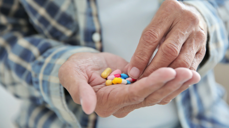 man's hand holding many different medications