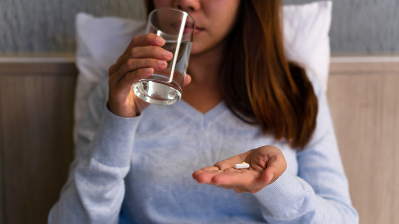 woman taking melatonin pill in bed