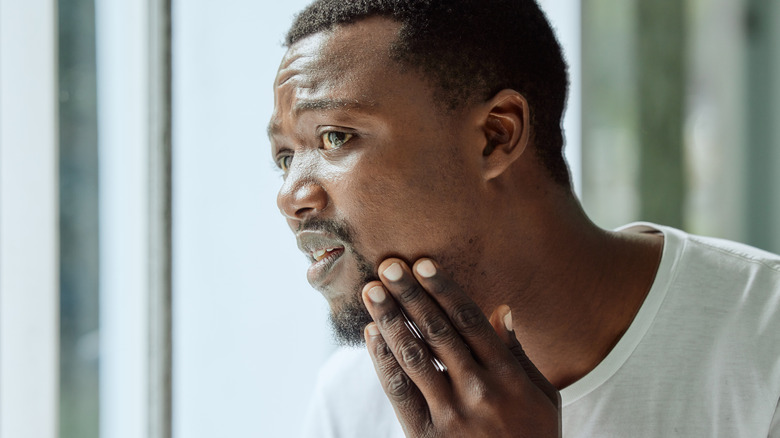 man looking in mirror with worried face