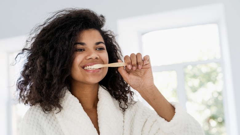 woman brushing her teeth in the mirror