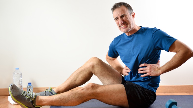 man wincing in pain while holding his ribs