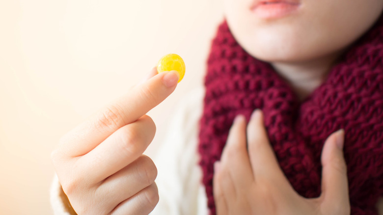 A woman takes a throat lozenge