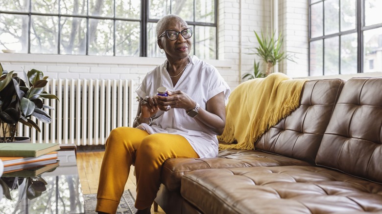 woman holding pill bottle looking pensive