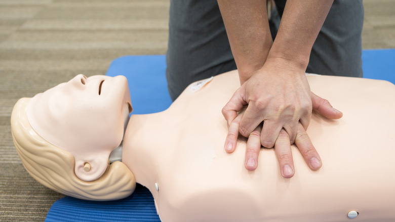 Person practicing CPR on a dummy torso
