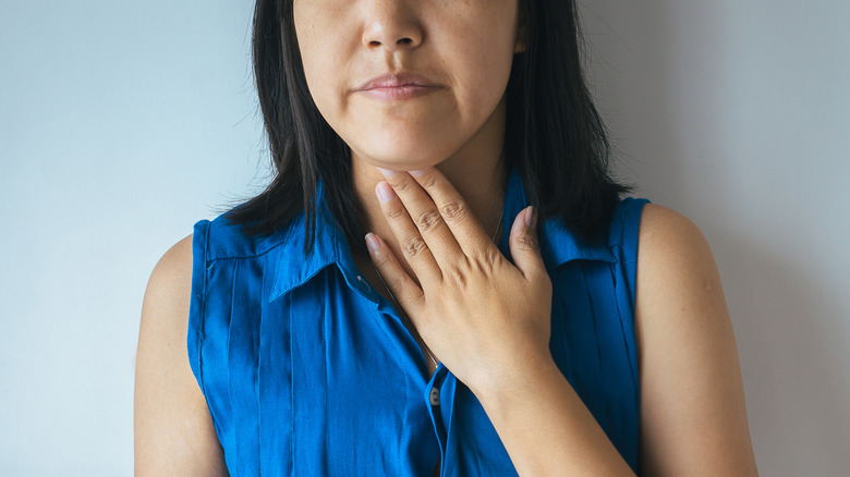 Woman holding hand to congested throat