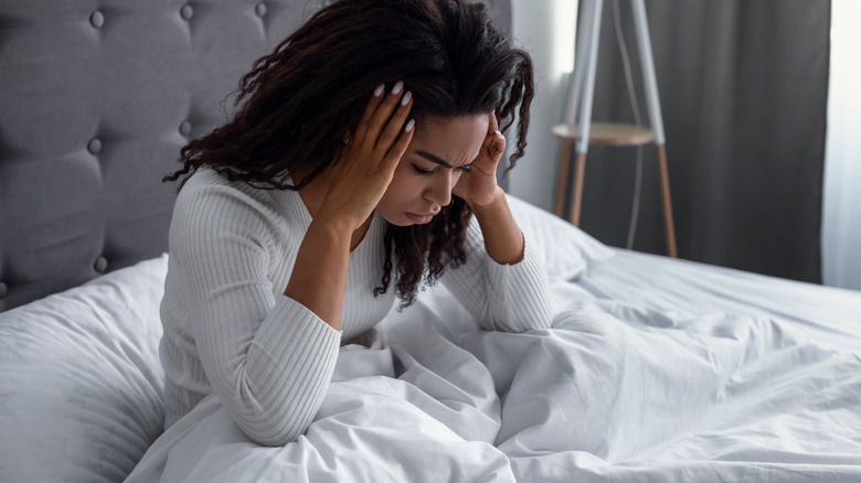 woman in bed holding her head