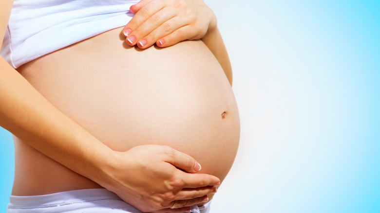 woman holding belly with blue background