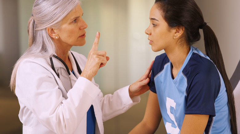 Doctor moving their finger in front of the eyes of a young athlete to test for a concussion