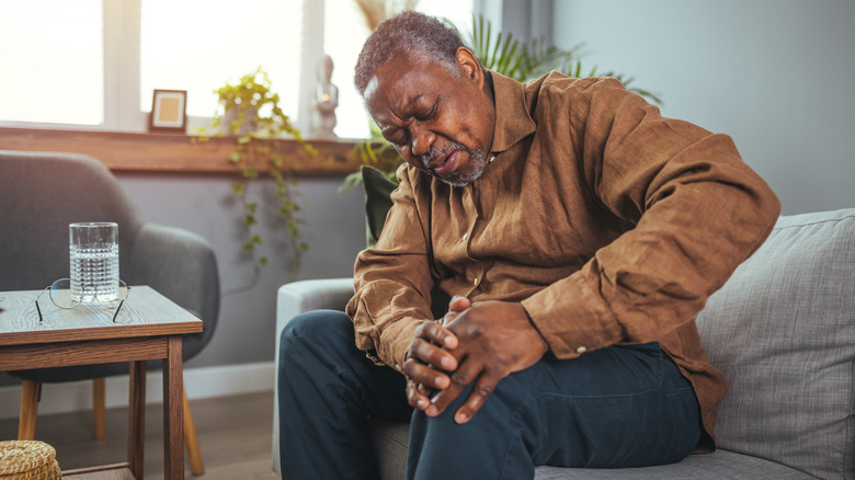 Senior man holds knee in pain