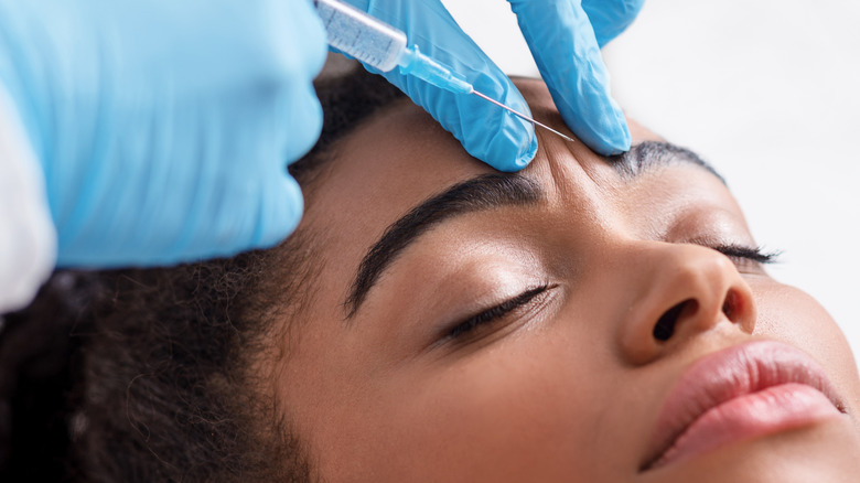 Closeup of woman receiving Botox injection in the forehead