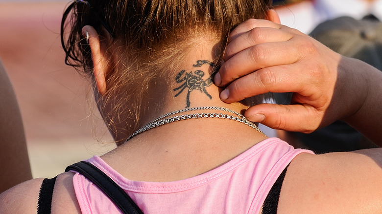 Hand scratching neck tattoo