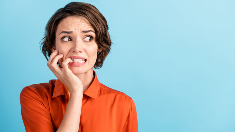 young woman biting fingernails and looking stressed