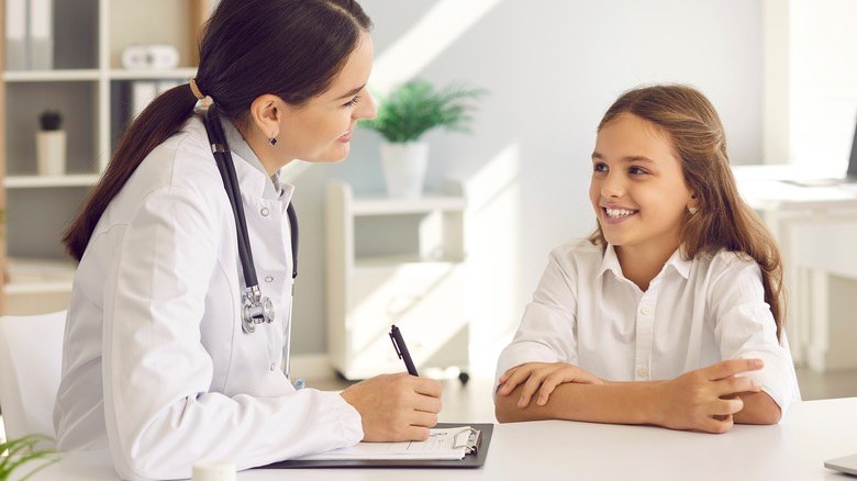 Pediatrician talking with smiling girl