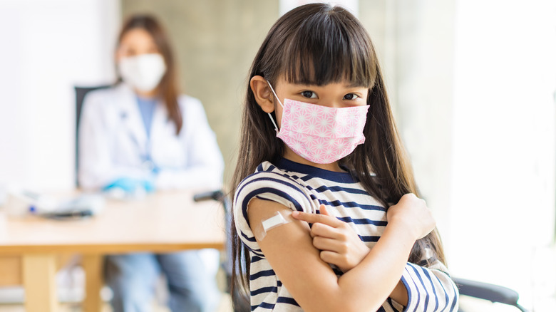 Girl pointing to vaccine bandage