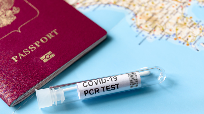 Passport and COVID-19 PCR COVID test laying on top of a map