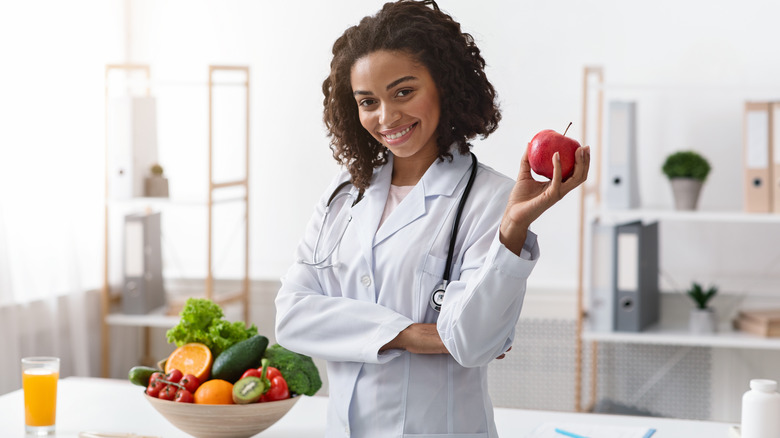 a young nutritionist smiling and holding an apple