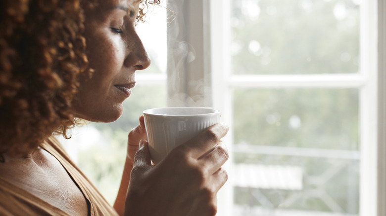 A woman savoring the smell of a hot beverage in her mug
