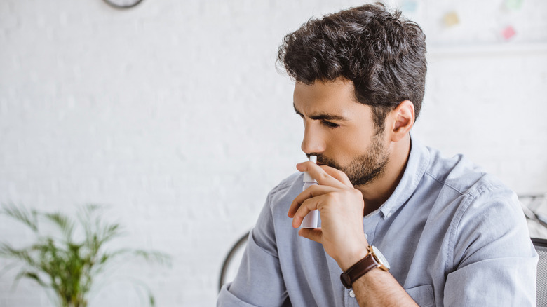 Man using nasal spray in office