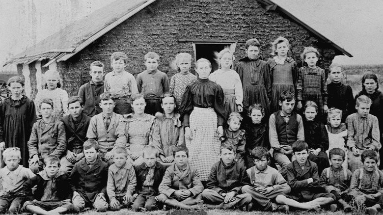 children and adults in front of small home in prairie in 1800s